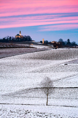 Colline innevate, tramonto rosa, chiesa a cupola